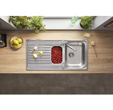 Roestvrijstalen spoelbak met afdruiprek, klein bassin met frambozen en kraan op een aanrecht