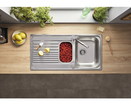 Roestvrijstalen spoelbak met afdruiprek, klein bassin met frambozen en kraan op een aanrecht