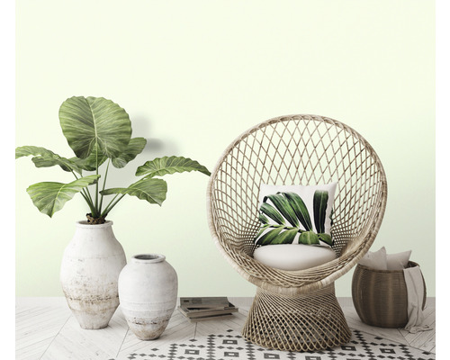 Decoratieve woonomgeving met rotan stoel, planten in vazen en vloertegels met motief.