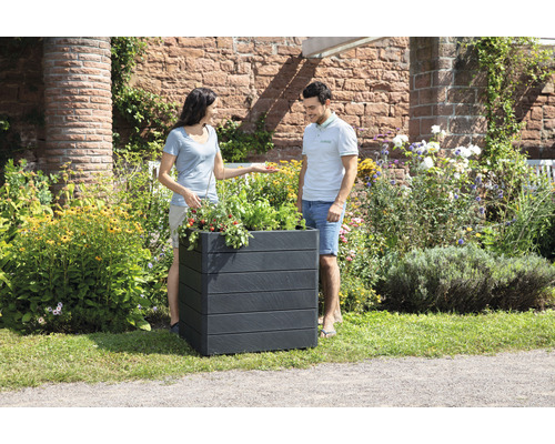 Een paar bekijkt een beplante, rechthoekige plantenbak in de tuin.