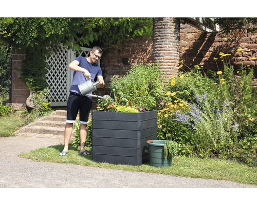Man geeft planten water in een plantenbak in de tuin.