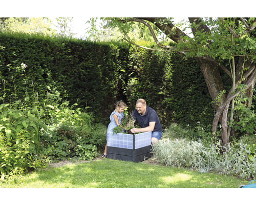 Vader en dochter werken samen in een verhoogde tuinbak in de tuin.