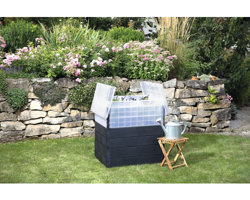 Verhoogde tuinbak met vroege broeibak en gieter in de tuin