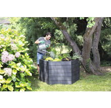 Man geeft planten water in een verhoogde tuinbak in de tuin.