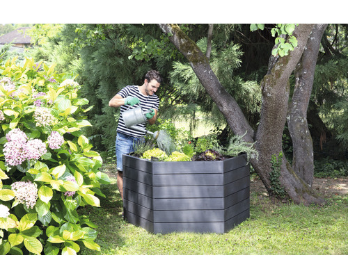 Man geeft planten water in een verhoogde tuinbak in de tuin.