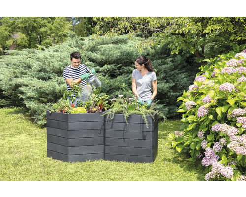 Twee personen in de tuin die een kunststof plantenbak beplanten