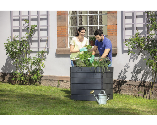 Scene met een plantenbak en twee mensen die planten plaatsen.