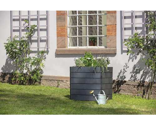 Vierkante houten plantenbak met gieter in de tuin