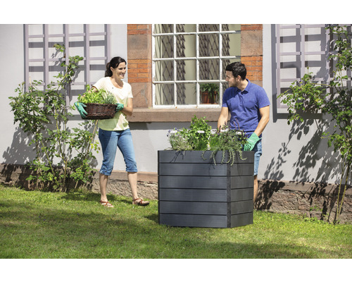 Tuinbeeld van een stel dat een plantenbak met kruiden beplant.