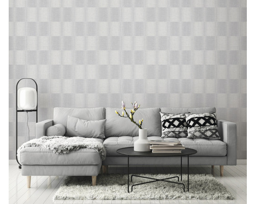 Lichte woonkamer met grijze bank, tafel en patroonbehang voor een vriendelijke sfeer.