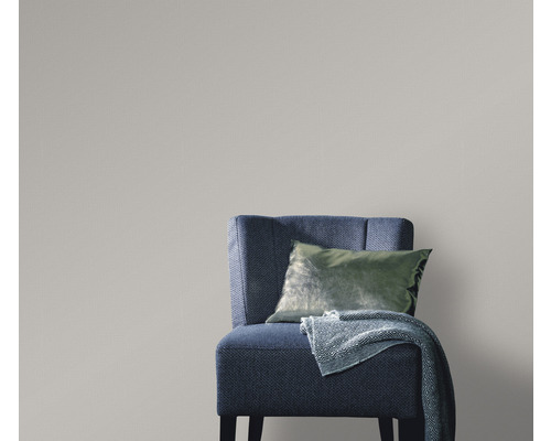 Scène met een blauwgrijze fauteuil met kussen en deken voor een grijze wandbekleding, die een heldere en georganiseerde sfeer creëert