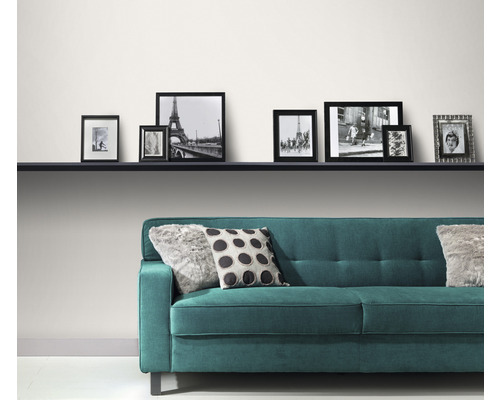 Moderne woonkamer met turquoise bank, kussens en een reeks fotolijsten op een plank