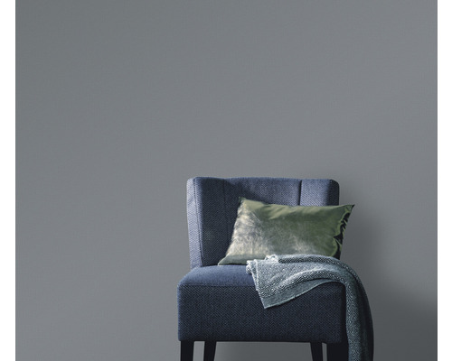 Effen behang achter een fauteuil met kussen en deken