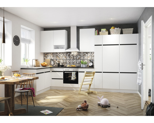 Lichte keuken met witte kasten, eettafel en speelgoed op de vloer.