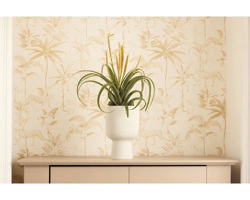 Decoratieve kamerplant in witte pot op een dressoir voor een behang met jungle motieven.