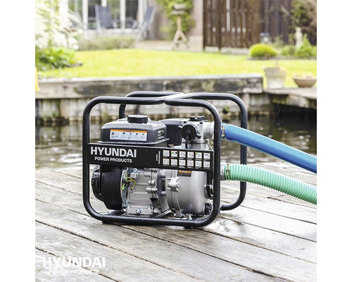 Hyundai waterpomp met slangen op houten planken aan het water