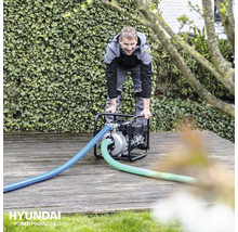 Man bedient een waterpomp van Hyundai in de tuin.