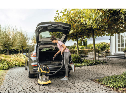 Vrouw stofzuigt het interieur van een auto met een alleszuiger.