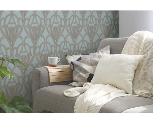 Woonkamer met bloemrijk behang, bank, kussens en deken