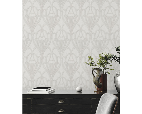 Inrichting met een patroonbehang in bloemige Art Nouveau-stijl achter een dressoir.