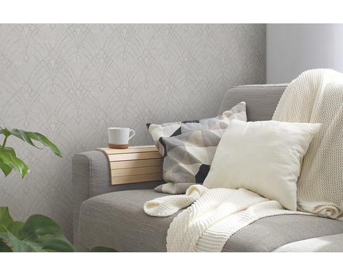 Woonkamer met patroonbehang, bank, kussens en plant voor een gezellige sfeer