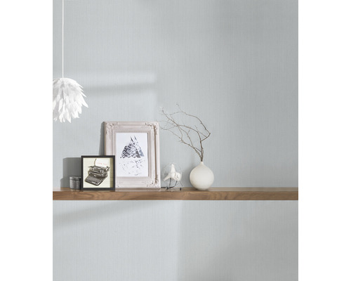 Lichte kamer met textielbehang, gedecoreerd met fotolijsten, vaas en plank