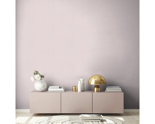 Lichte kamer met roze muur, dressoir, tafellamp en decoratieve objecten