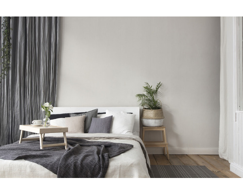 Slaapkamer met bed, kussens, deken, gordijnen en planten