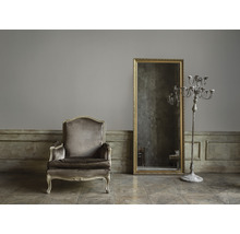 Interieur met fauteuil, spiegel en kandelaar in een kamer.