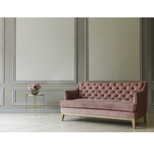 Roze fluwelen bank met knoopsluiting in een lichte, ruime kamer