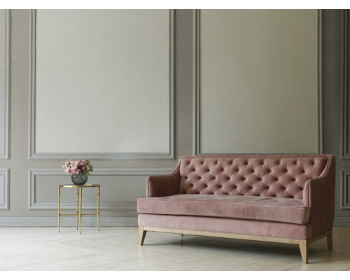 Roze fluwelen bank met knoopsluiting in een lichte, ruime kamer