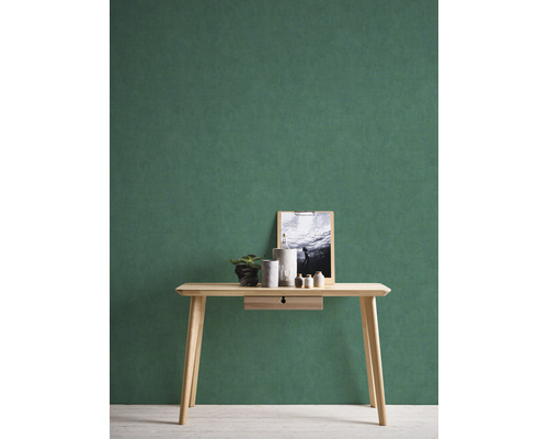 Licht houten bureau met decoratie en een afbeelding tegen een groene muur