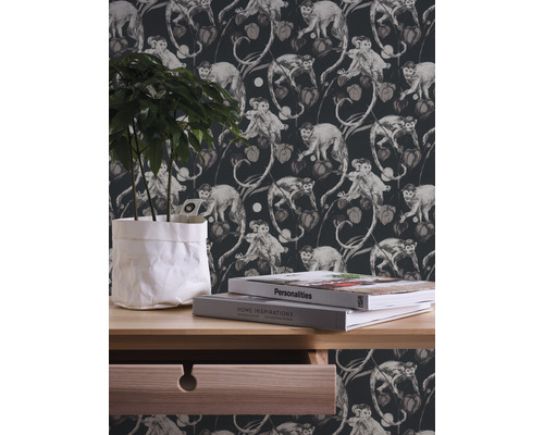 Decoratief behang met apen- en plantmotieven op de achtergrond, plus een dressoir met plant en boeken.