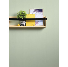 Wandplank met plant, geel notitieblok en foto aan een groene muur