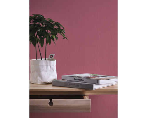 Decoratieve kamerplant in witte papieren zak op een houten tafel met twee boeken voor een gestructureerde wand