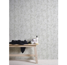 Behang met bamboepatroon achter een houten tafel met verzorgingsproducten en een doek