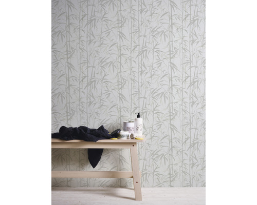 Behang met bamboepatroon achter een houten tafel met verzorgingsproducten en een doek