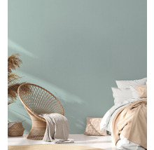Lichte slaapkamer met rotan stoel, bed en droogbloemen