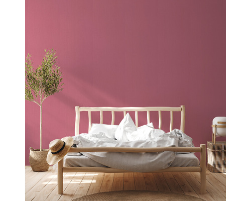 Slaapkamer met houten bed, plant en roze muur