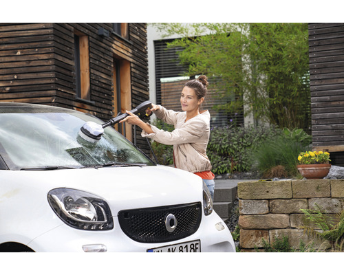 Vrouw reinigt een auto met een roterende wasborstel en een hogedrukreiniger