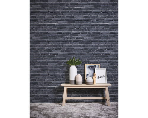 Decoratief behang met steeneffect boven een tafel met vazen en schilderijen.