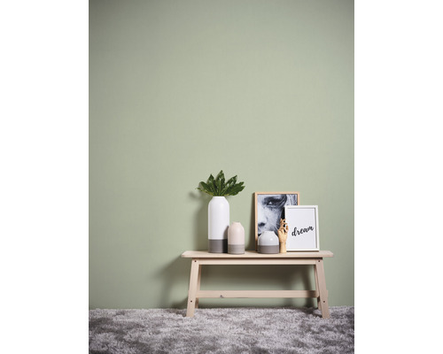 Decoratieve vazen en fotolijsten op een houten bank voor een groene muur.