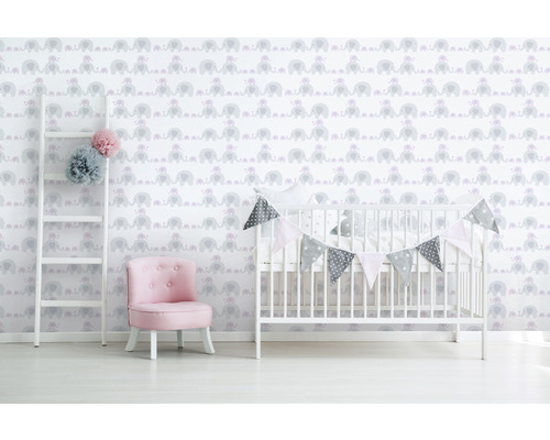 Kinderkamer met olifantenbehang, ladder, fauteuil en babybedje.