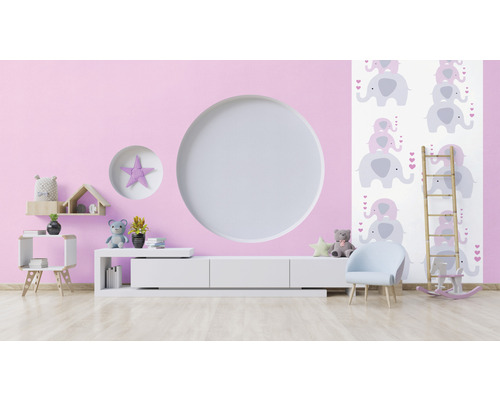 Lichte kinderkamer met roze muur, witte kast, stoel en olifantenbehang