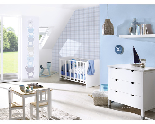 Een kinderkamer met een kinderbed, een commode, een tafel en stoelen.