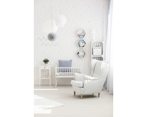 Licht ontworpen kinderkamer met wieg, fauteuil en witte meubels