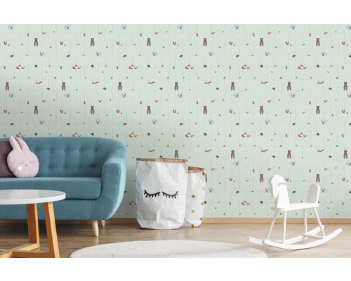 Kinderkamer met behang met bosdiermotieven, een turquoise bank, een ronde tafel en een hobbelpaard.