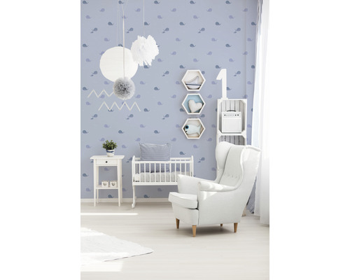Kinderkamer met witte fauteuil, babybed en blauw behang met print