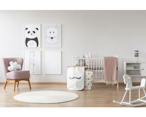 Lichte kinderkamer met babybed, fauteuil, speelgoed, vloerkleed en dierenafbeeldingen aan de muur