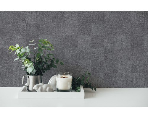 Decoratieve opstelling met een kaars, een plant en grijs behang met linnenstructuur